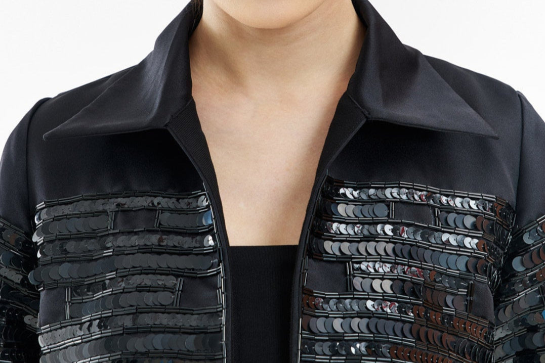 Woman wearing a black sequined jacket on a white background